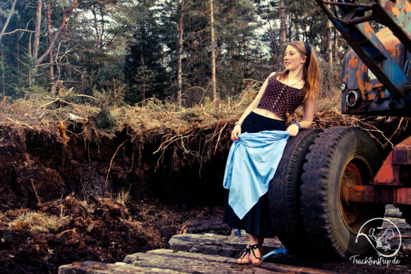 Schöne Frau mit Dirndl und sexy Sandalen an Moorbagger