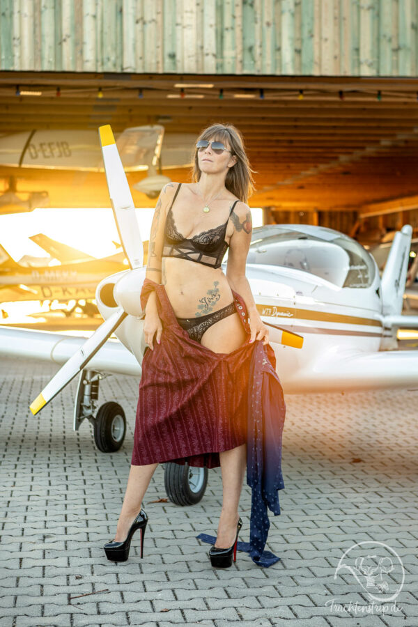 Pilot in Dirndl and lingerie in front of a private plane