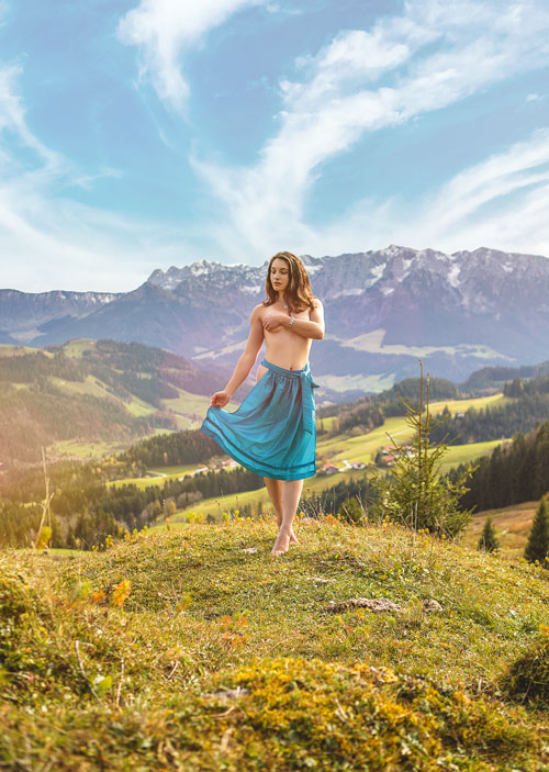 Country girl with a dirndl apron naked in front of a mountain backdrop